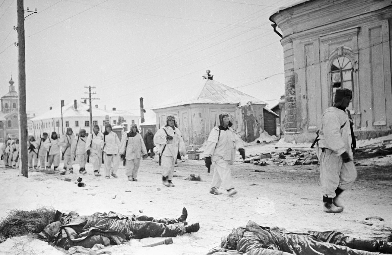 Soviet soldiers passing by dead Nazis along liberated streets of Kalinin.