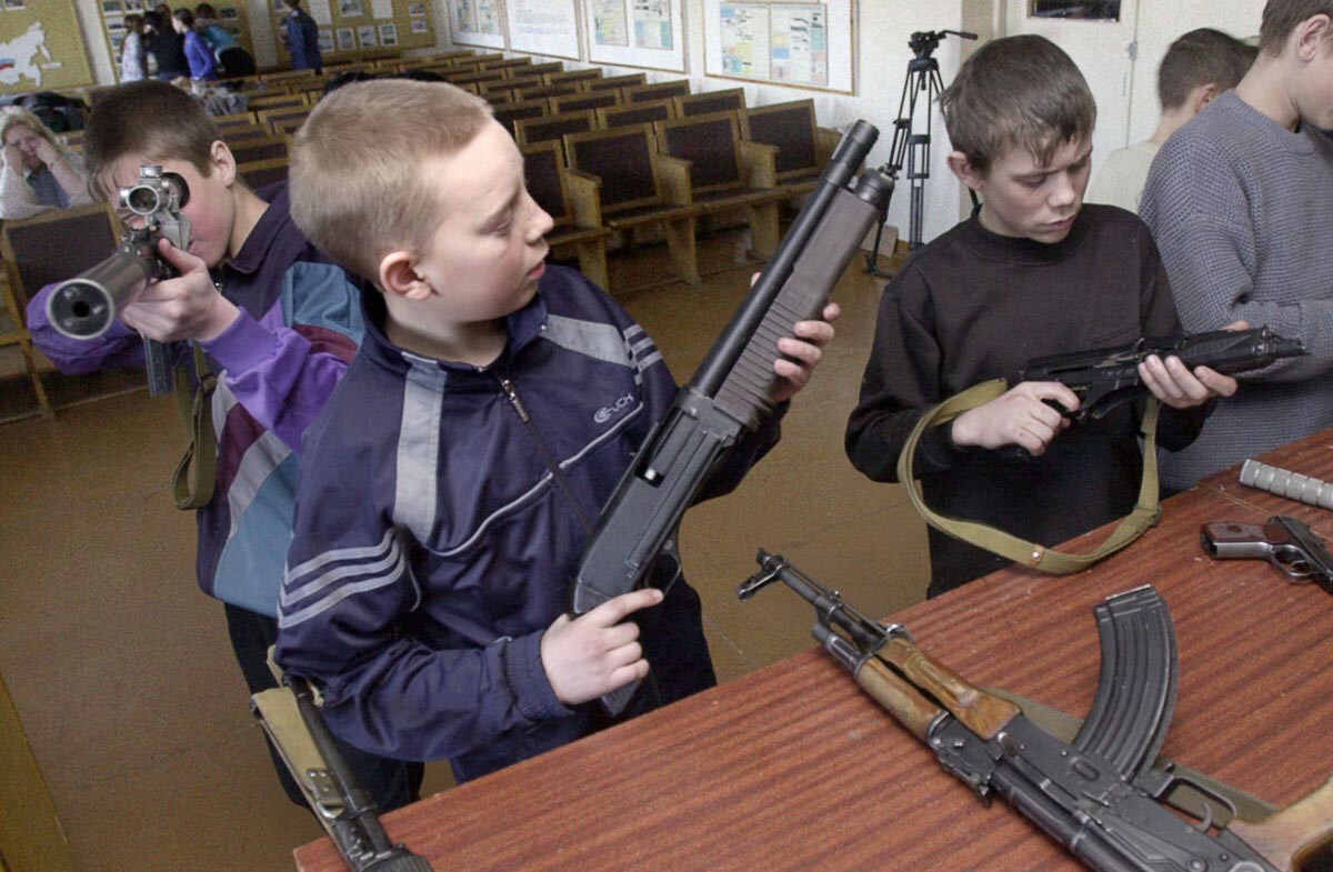 Ragazzini delle scuole studiano il funzionamento di un fucile