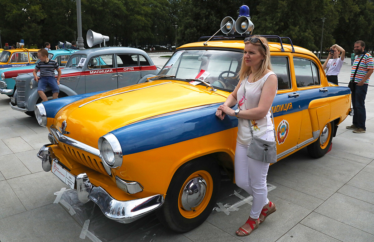 Ein Mädchen wird in der Nähe eines GAZ M21 Wolga-Wagens während einer Ausstellung von Retro-Fahrzeugen fotografiert, die zeitlich mit der Feier des Moskauer Verkehrstages im VDNKh in Moskau zusammenfällt.