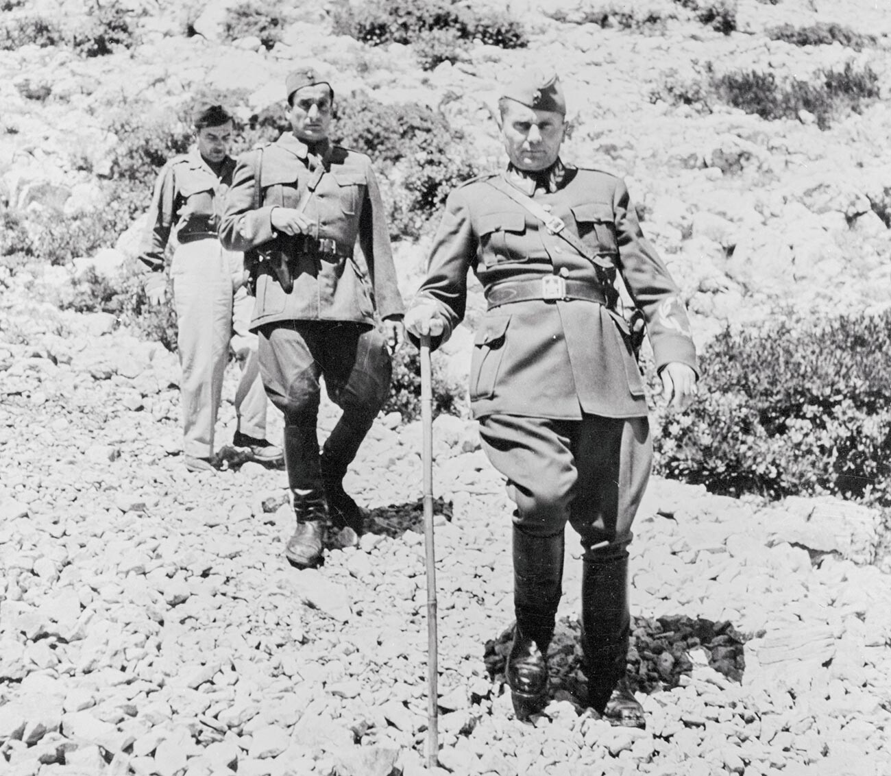 Josip Broz Tito contando una broma mientras pasea con sus acompañantes