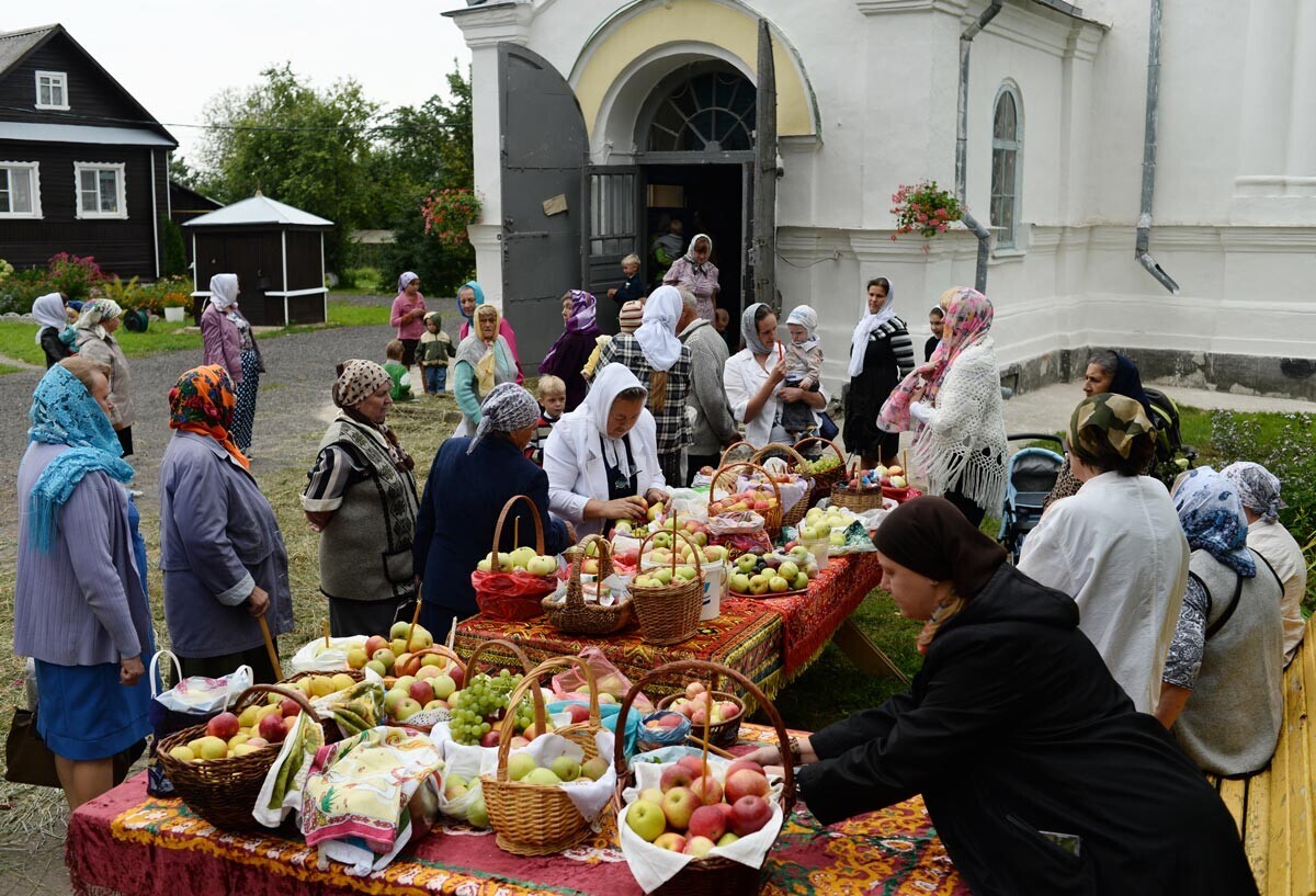 Orang-orang yang berkeyakinan bersiap untuk menguduskan apel selama pesta Transfigurasi. Gereja Transfigurasi di Desa Bronnitsa, Novgorod Oblast.