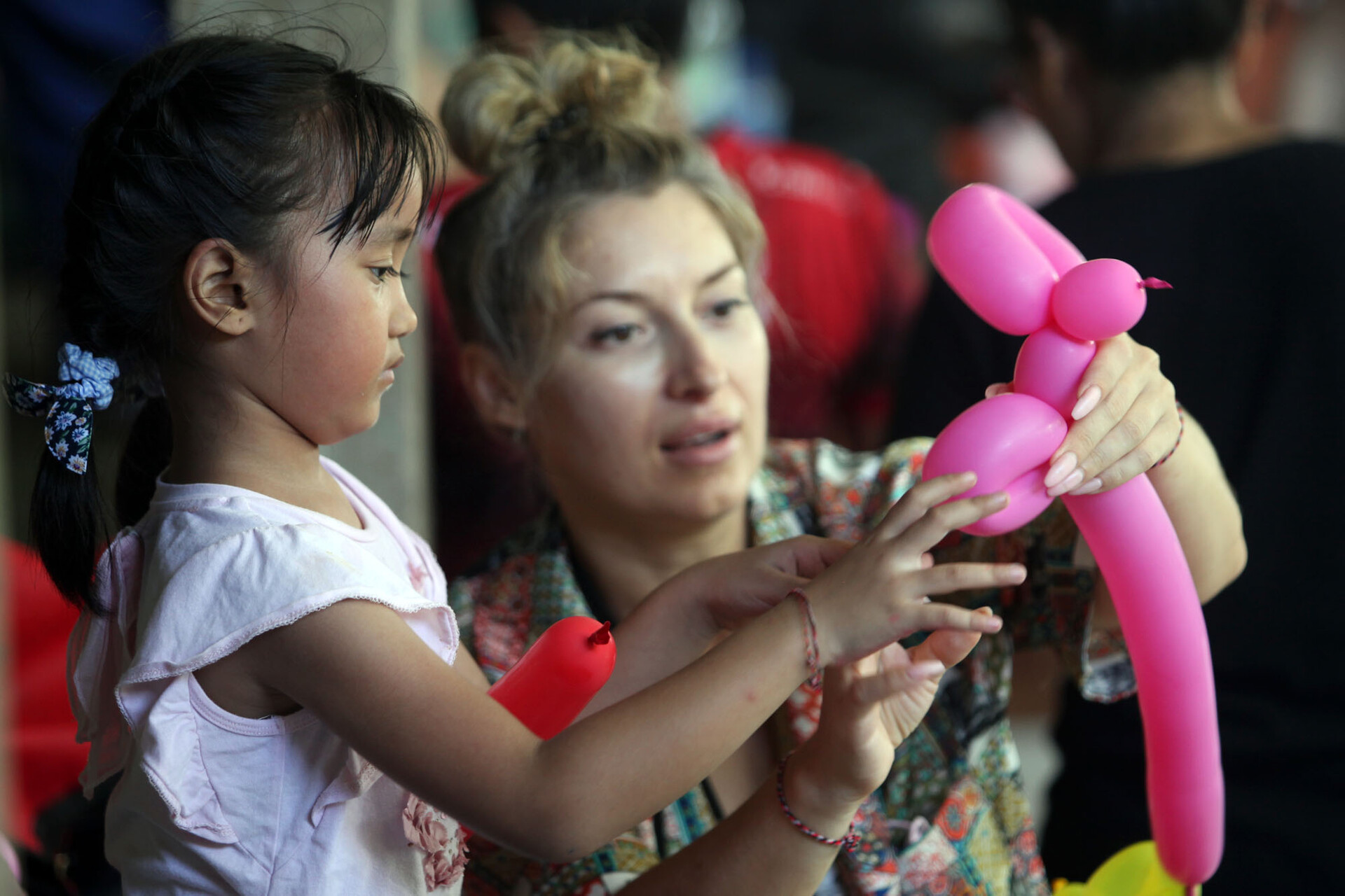 Sukarelawan mengajarkan seorang anak untuk membentuk balon.