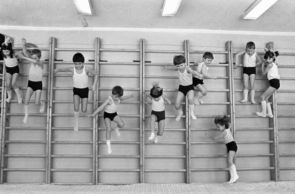 Kinder springen von einer Sprossenleiter im Sportunterricht. 