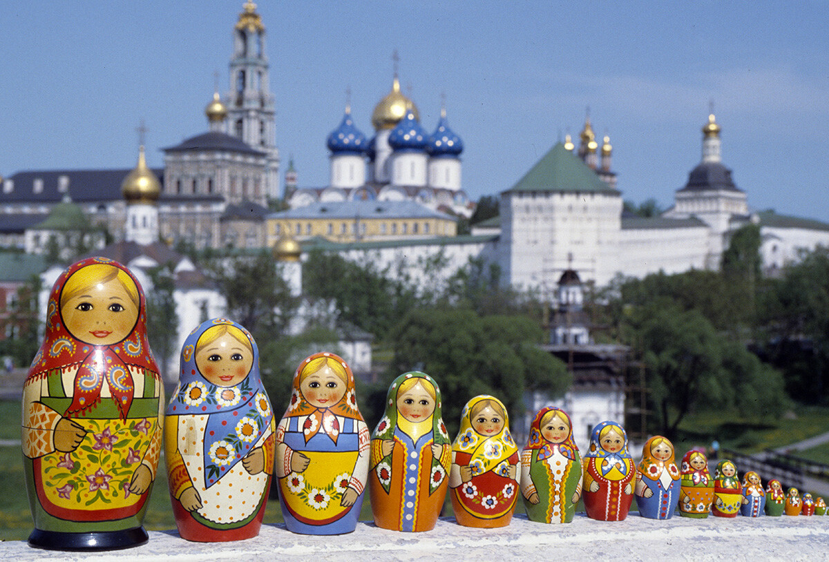 至聖三者聖セルギイ大修道院を背景に写真におさまるマトリョーシカ人形。