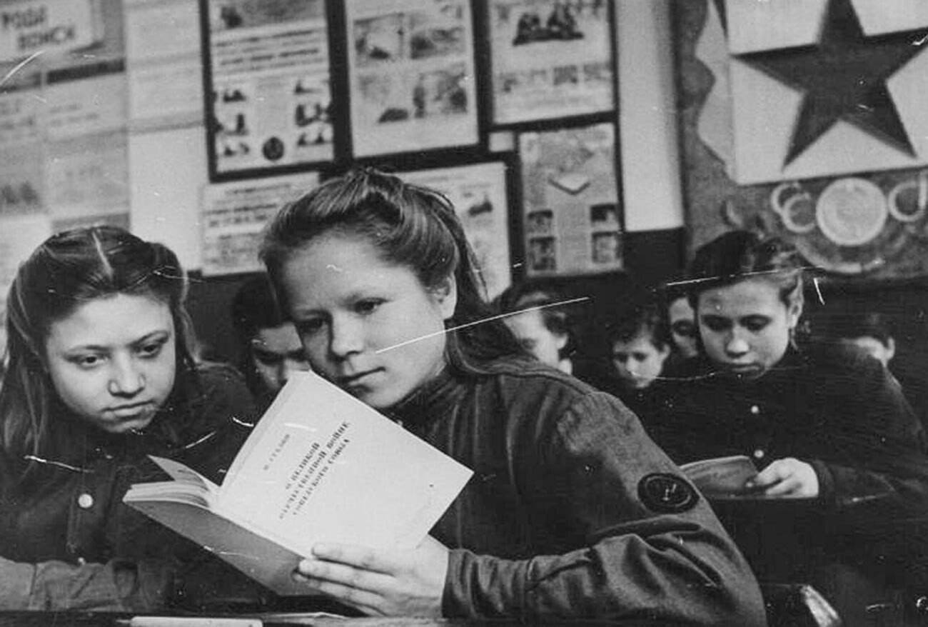 Des étudiants d'une école soviétique lisant un livre de Staline