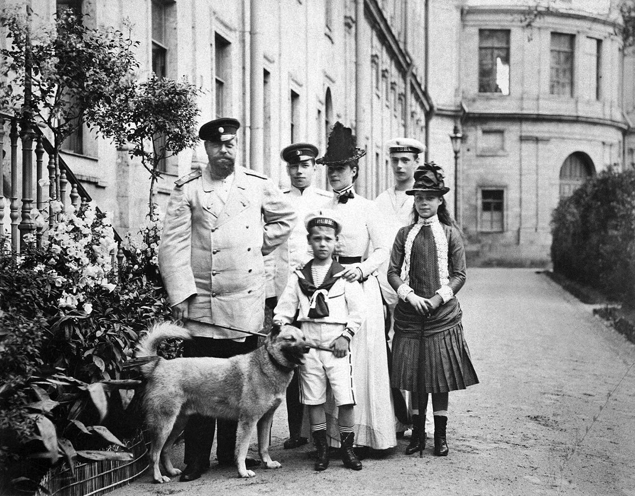 Zar Alexander III., Zarewitsch Nikolaus, Großfürst Michael und Hund, Kaiserin Marie Feodorowna, Großfürst Georg und Großfürstin Xenia. Die Aufnahme entstand vor dem kaiserlichen Palast in Gatschina.