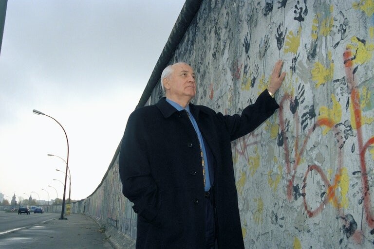 Mikhail Gorbachev berdiri di sebelah monumen Tembok Berlin.