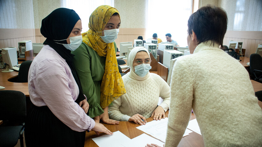 Tiga orang mahasiswa menghadiri kelas komputer di Universitas Negeri Tambov, Rusia.