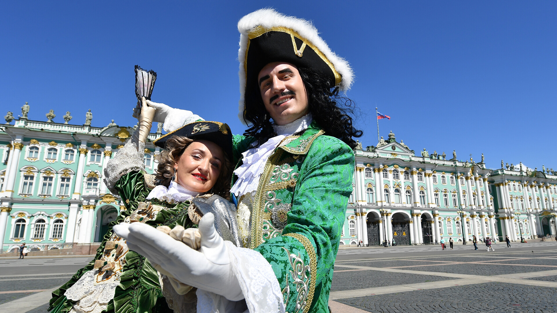 Par v starinskih kostumih pozira pred muzejem Ermitaž 19. junija 2017 v Sankt Peterburgu v Rusiji