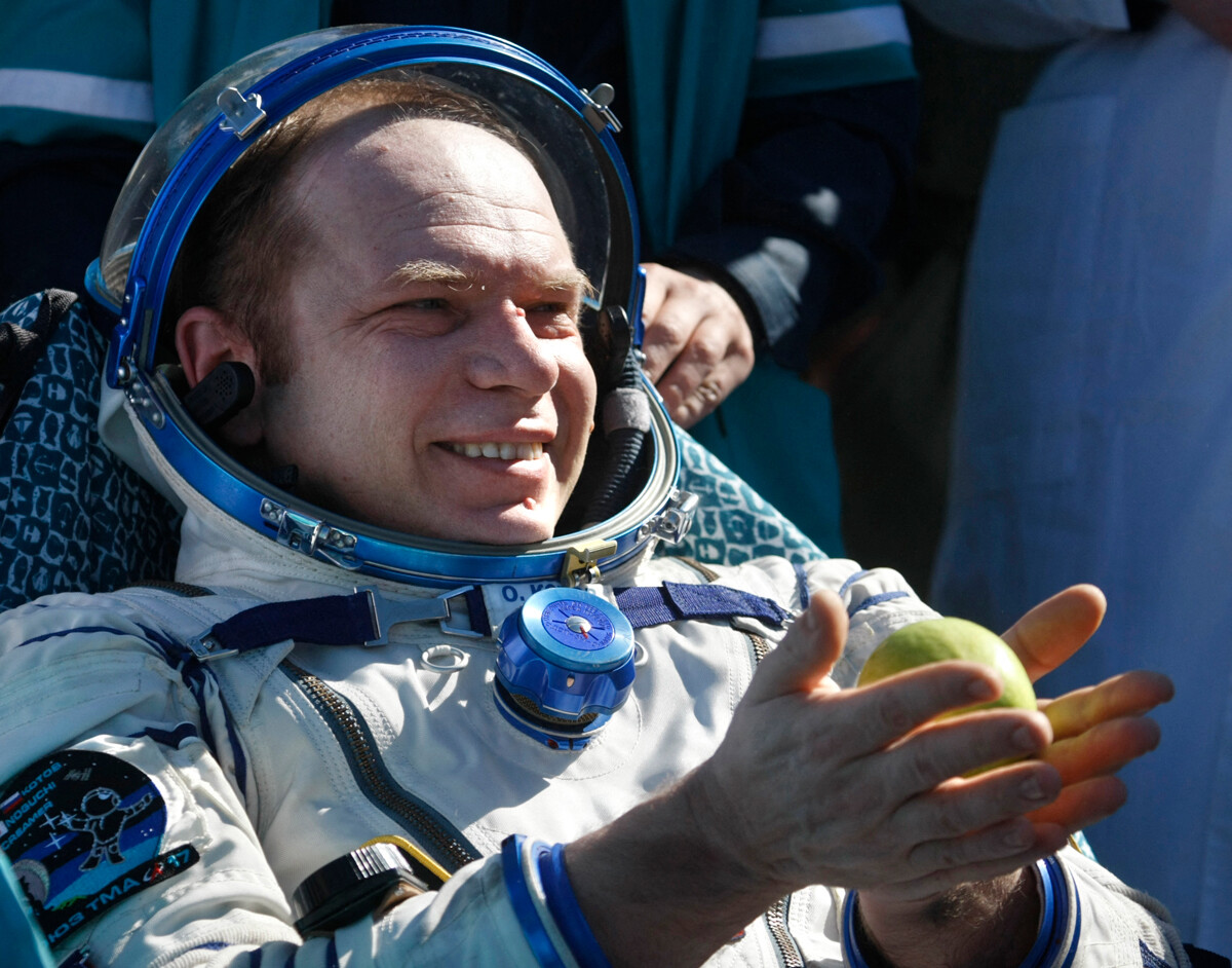 Oleg Kotov segura uma maçã logo após o pouso da cápsula espacial russa Soyuz TMA-17 em 2010.