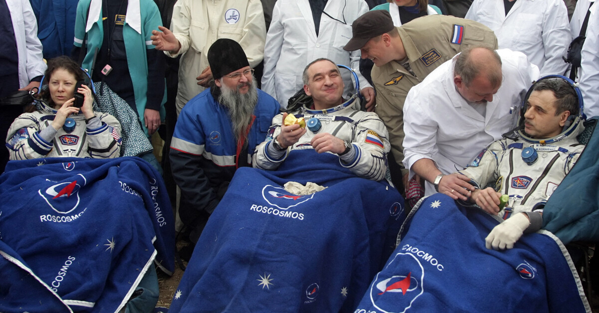 A astronauta da Nasa Tracy Caldwell Dyson fala ao telefone enquanto os cosmonautas russos Aleksandr Skvortsov (centro) e Mikhail Kornienko (dir.) comem maçã e pepino após o pouso da espaçonave Soyuz TMA-18 no Cazaquistão, em 25 de setembro de 2010.