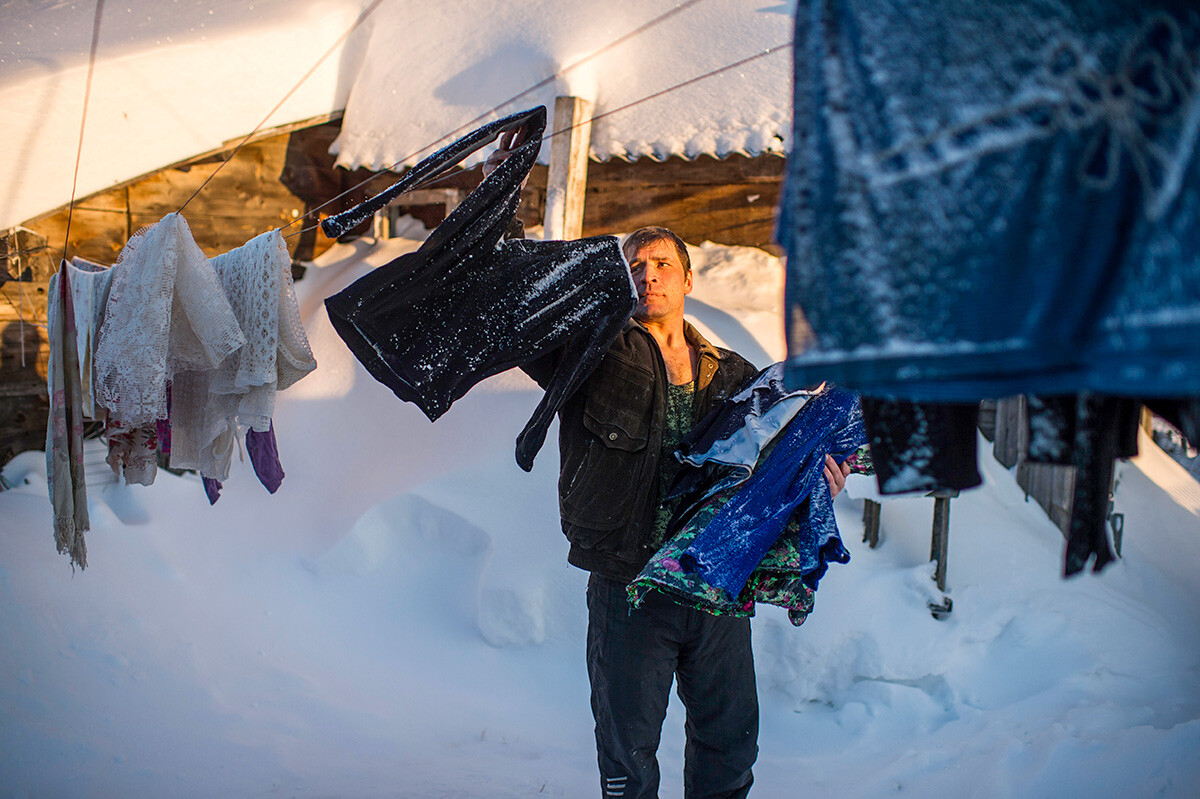 Prebivalec vasi Kurjan-Dubovka pospravlja posušena na mrazu oblačila