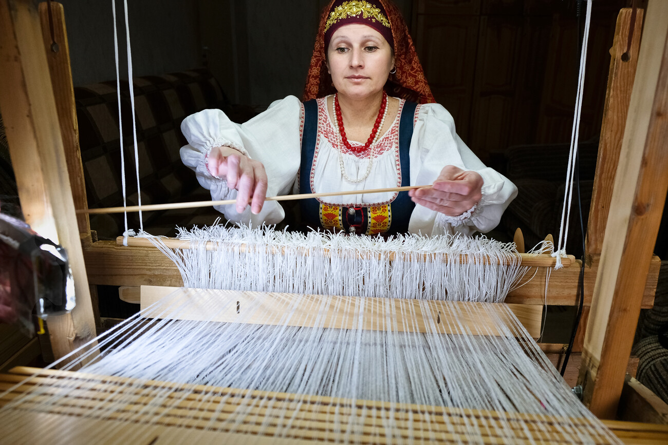 トヴェリの技能展でハンドメイドの衣装を着て機織りをする女性