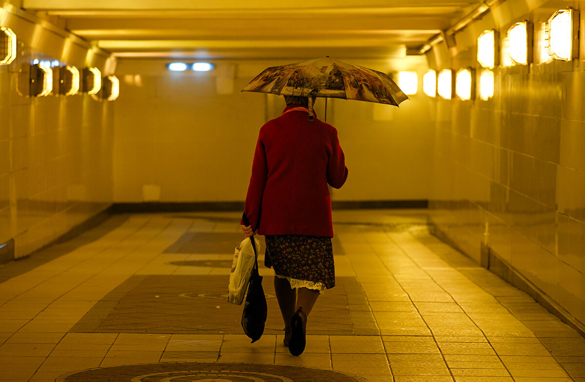 18. oktober 2022: Ženska pod dežnikom si poišče zavetišče v deževnem vremenu, podzemni prehod v Moskvi, Rusija