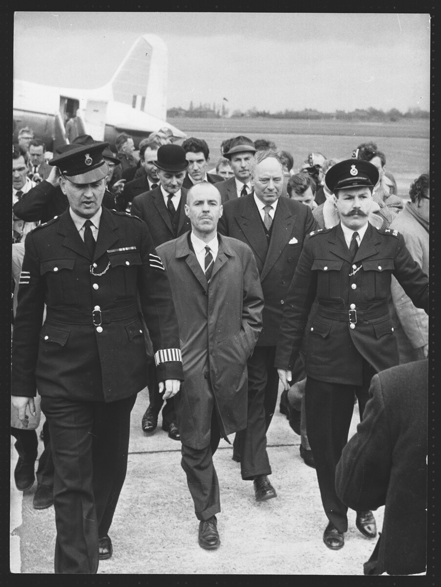 Greville Wynne sale del aeropuerto de Northolt con escolta policial.