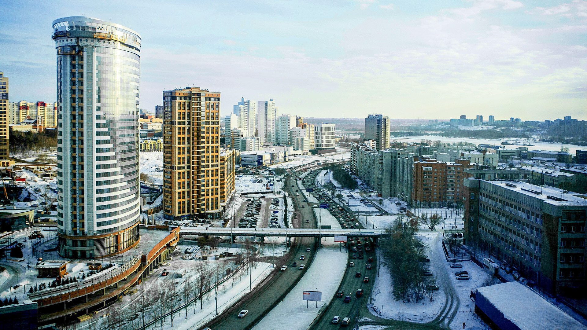 Mestna pokrajina Novosibirska, visoke pisarniške in stanovanjske stavbe ter nebotičniki v mestu, cesta za avtomobile in most za pešce v zimskem času