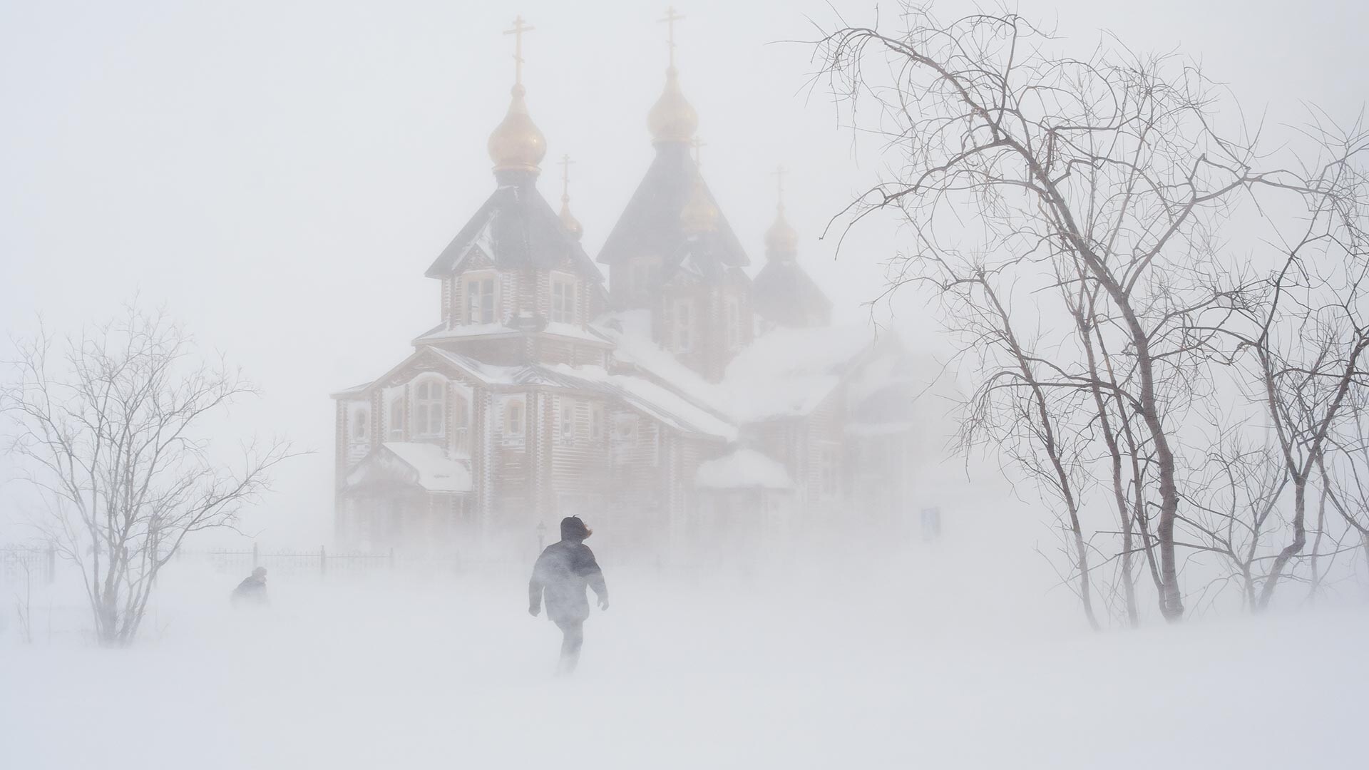 Pozimi med snežnim metežem v bližini katedrale Svete Trojice. Ljudje gredo skozi snežni metež. Anadir (Čukotka, Rusija)