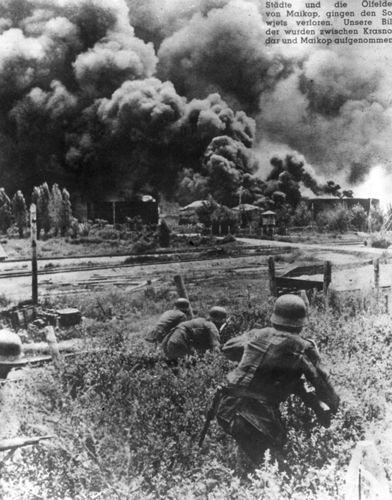 Deutsche Soldaten nähern sich einem brennenden Öldepot bei Maikop.