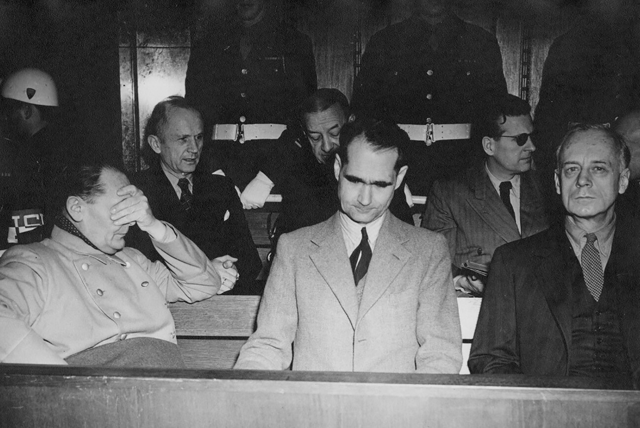 Obtoženci na nürnberških sojenjih za vojne zločine. Od leve proti desni: Hermann Göring, admiral Karl Doenitz, admiral Erick Raeder, Rudolf Hess, Baldur von Schirach in Joachim von Ribbentrop. Moški na sredini je domnevno dvojnik Rudolfa Hessa.