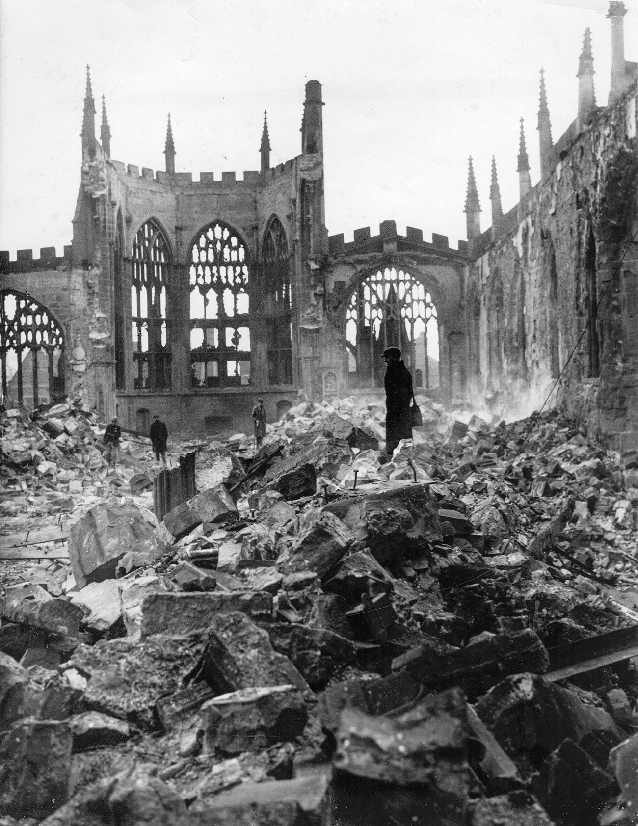 Persone camminano tra le rovine della Cattedrale di Coventry, distrutta da un pesante bombardamento aereo tedesco