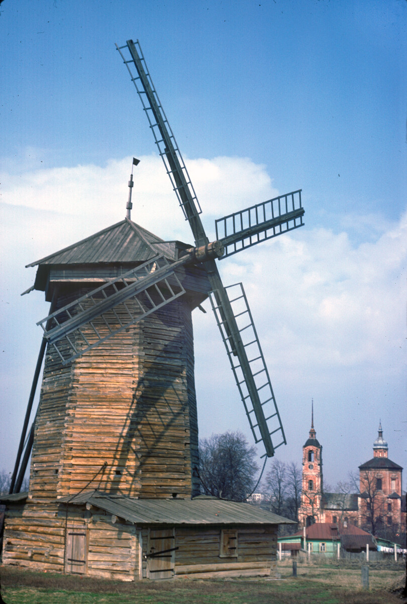 Moulin à vent en bois qui tourne en haut. Originellement construit au XIXesiècle au village de Mochok, district de Soudogorodski. Arrière-plan : église en briques des Saints Boris et Gleb (1749)