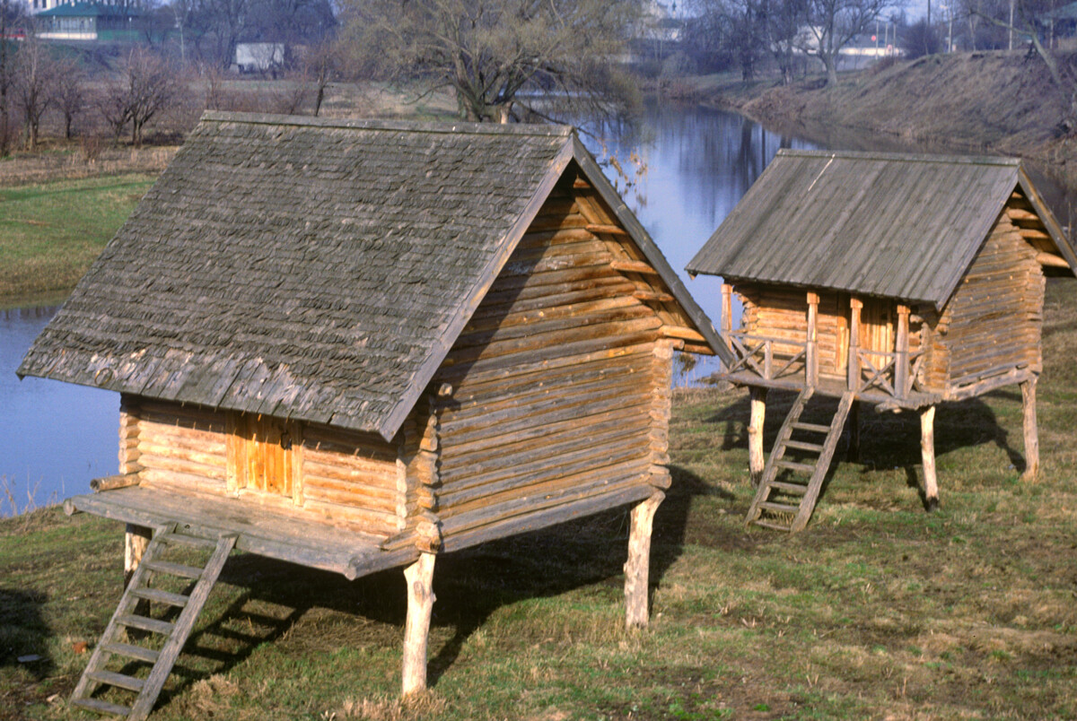 Capanne di stoccaggio su palafitte di tronchi. Originariamente sorgevano nel villaggio di Moshok del distretto Sudogodskij. Sullo sfondo il fiume Kamenka, che scorre a Suzdal. Foto del 27 aprile 1980

