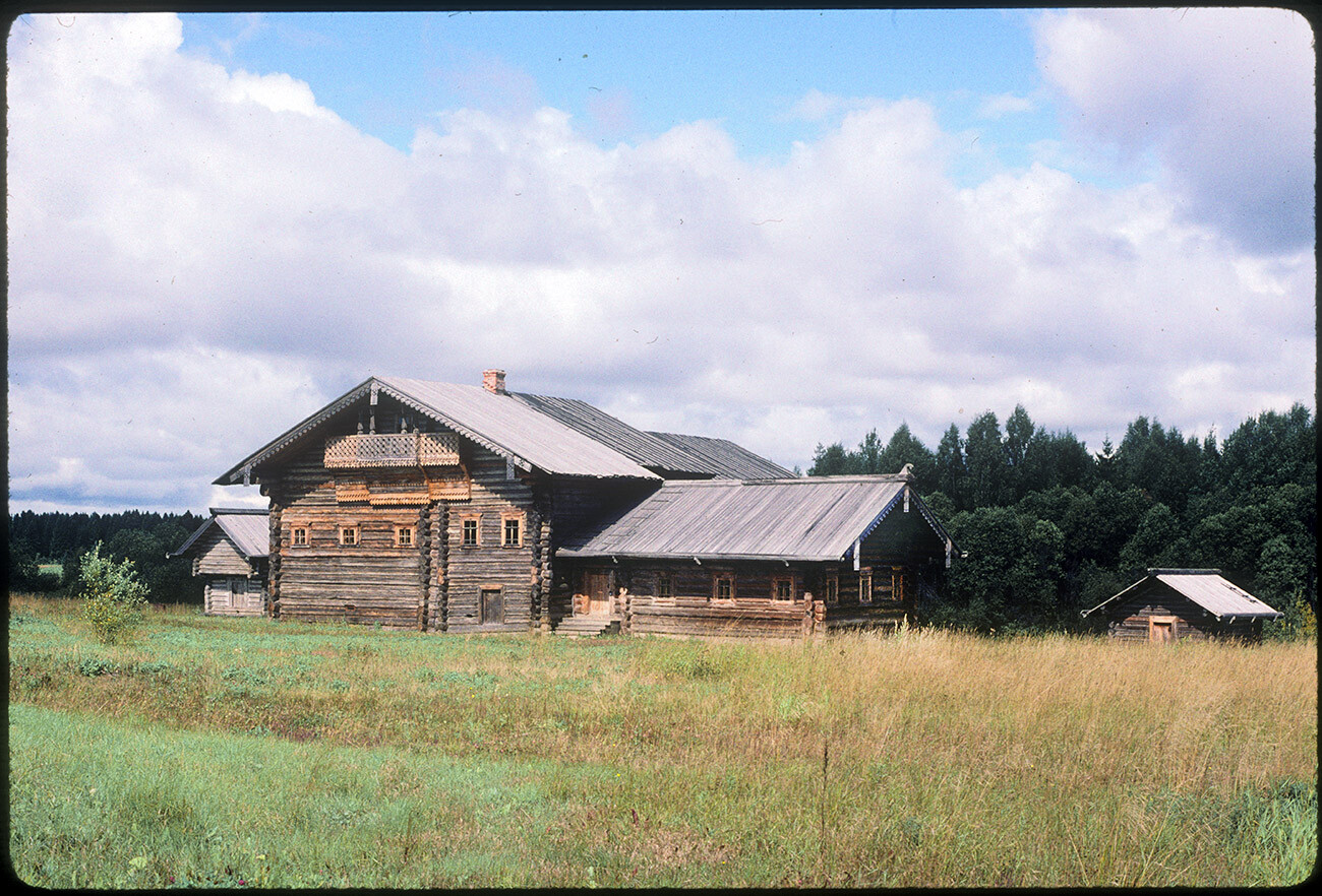 Semyonkovo. A. E. Bolotova house. Originally built in village of Korolevskaya (Nyuksenitsa District) in early 19th century with later additions. Zimnik (winter quarters) extending from right side. Log barn partly visible on left. August 11, 1995