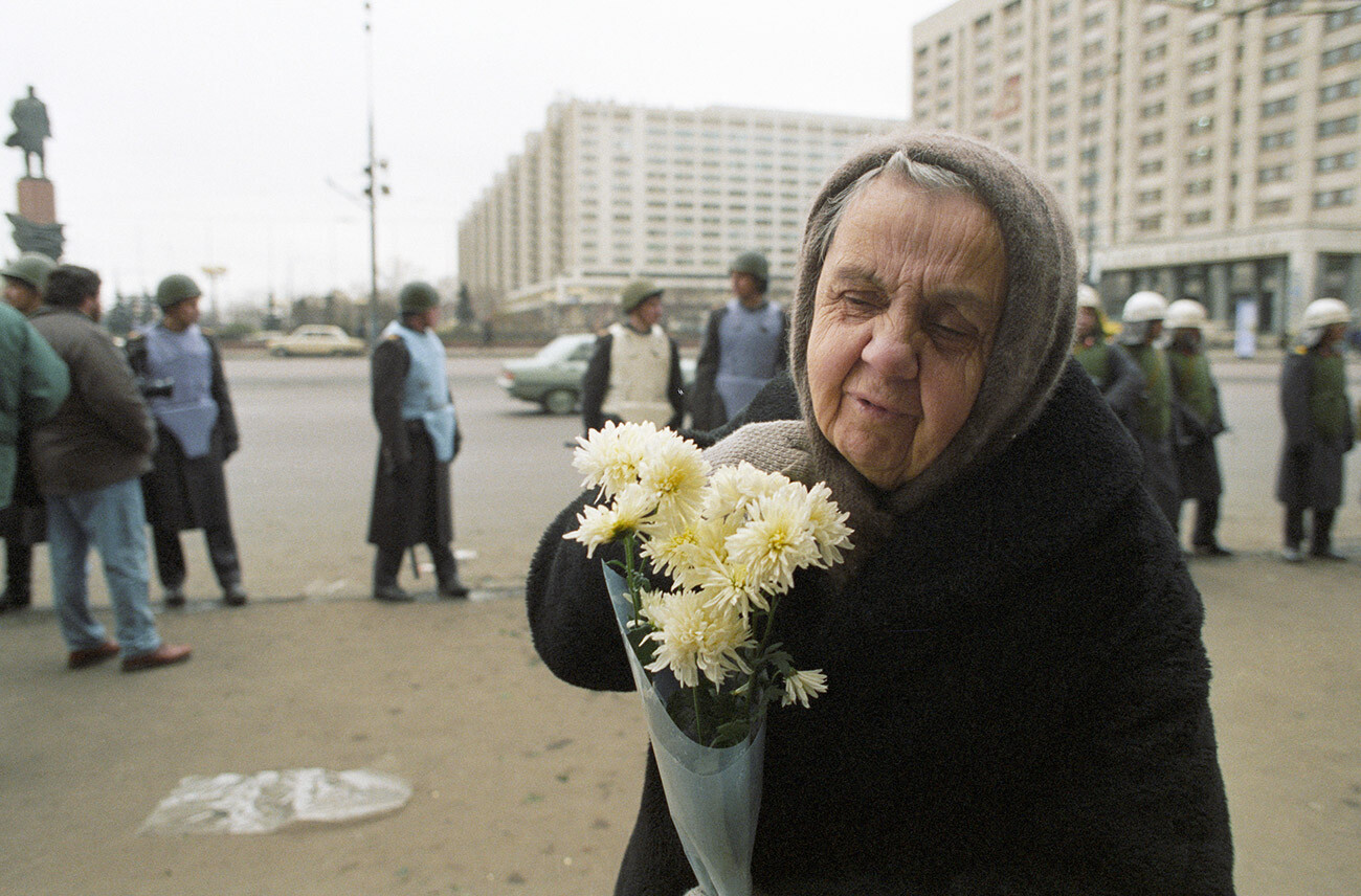Une participante âgée à un rassemblement dédié à la célébration du jour de la Grande Révolution socialiste d'Octobre porte un bouquet de fleurs au monument à Vladimir Lénine sur la place Oktiabrskaïa (d'Octobre)
