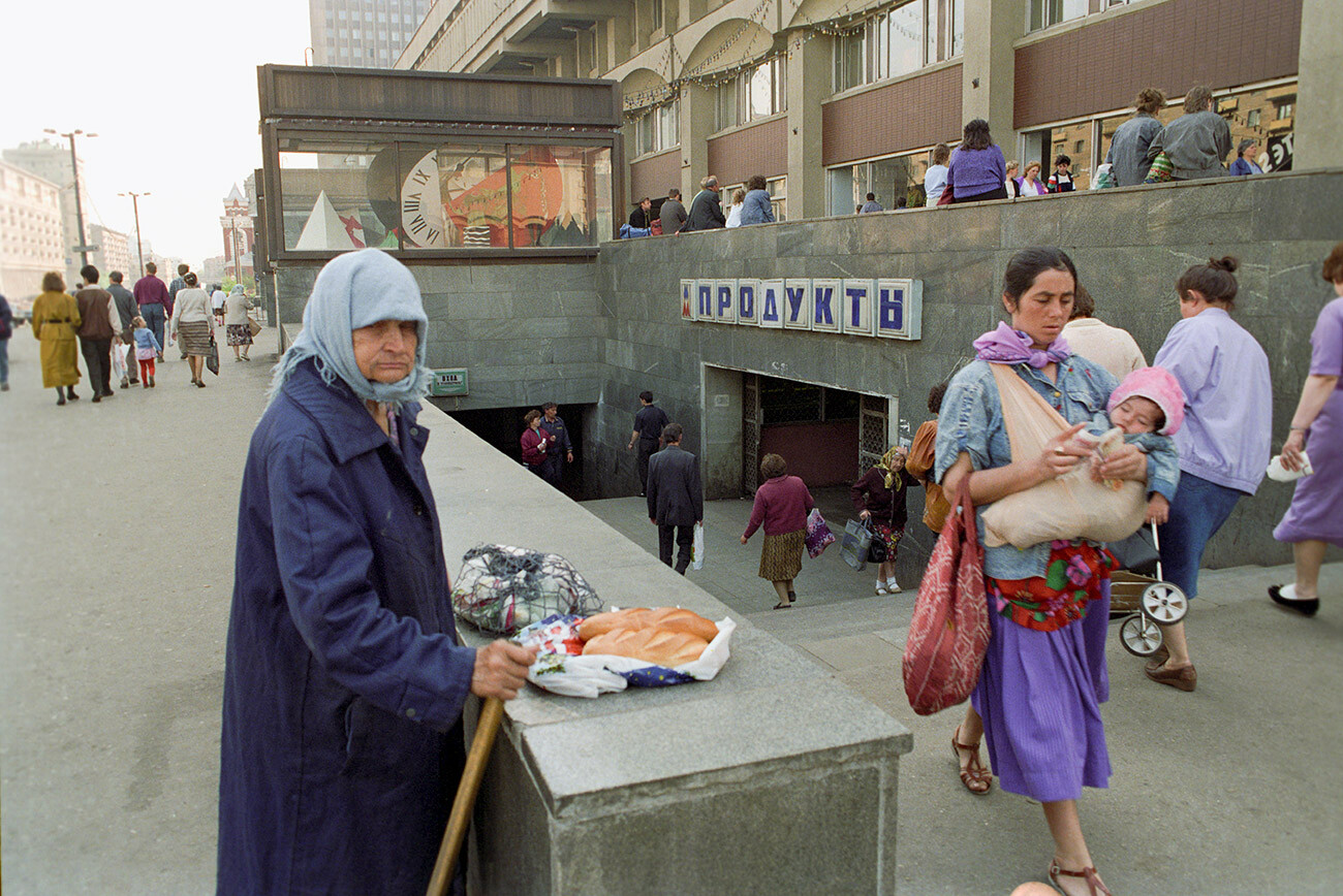 Une femme âgée vend des produits d'épicerie à l'entrée du grand magasin Moskovski (de Moscou) sur la place Komsomolskaïa (du Komsomol)