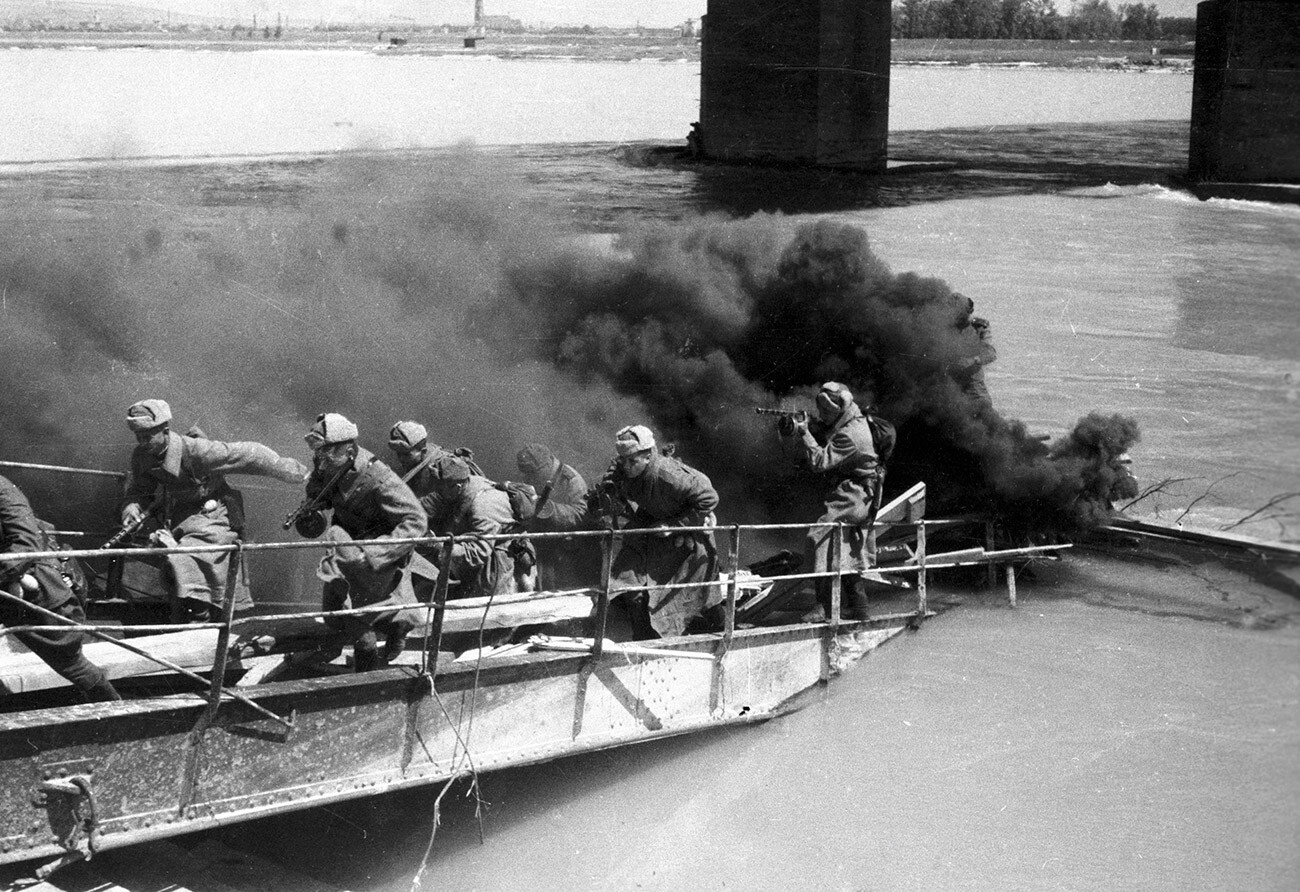 Soldiers of the 4th Guards Army running up the ship's ladder under cover of a smoke-screen during a battle for the Danube Channel. 