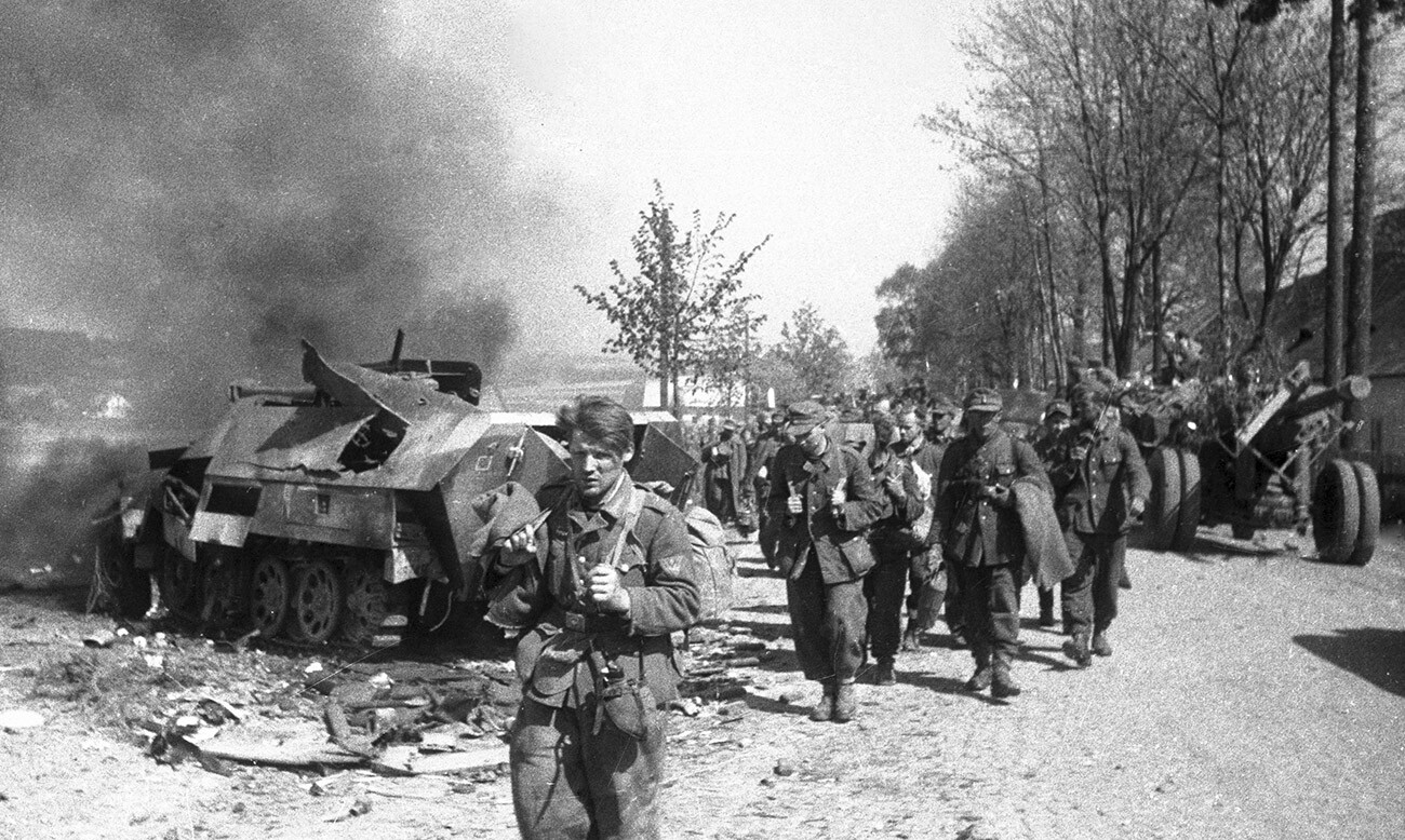Die Befreiung der Tschechoslowakei von den Nazi-Invasoren. Kriegsgefangene der Hitler-Armee, die an zerstörtem Kriegsgerät vorbeilaufen.