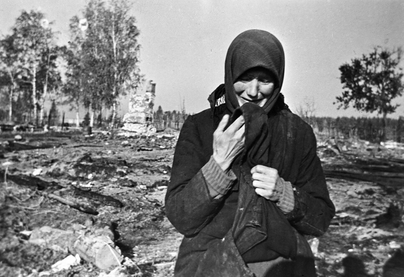 Eine Frau weint vor den Ruinen ihres von den Nazis niedergebrannten Heimatdorfes.