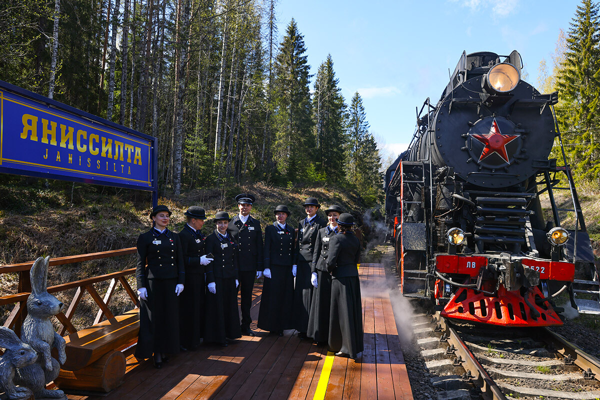 KARELIJA, RUSIJA - 22. MAJ 2022: Sprevodniki na postaji Janissilta ob vlaku Ruskeala Express. Ruskeala Express je potniški izletniški vlak na parni pogon, ki vsak dan vozi med Sortavalo in gorskim parkom Ruskeala. Njegova notranjost posnema carski ruski slog vlaka Nikolajevski ekspres. 