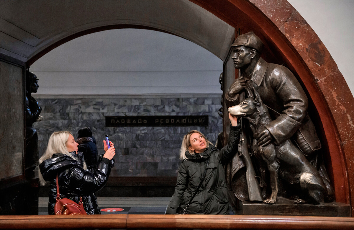Dekleti se fotografirata s skulpturo obmejnega stražarja s psom na postaji metroja 
