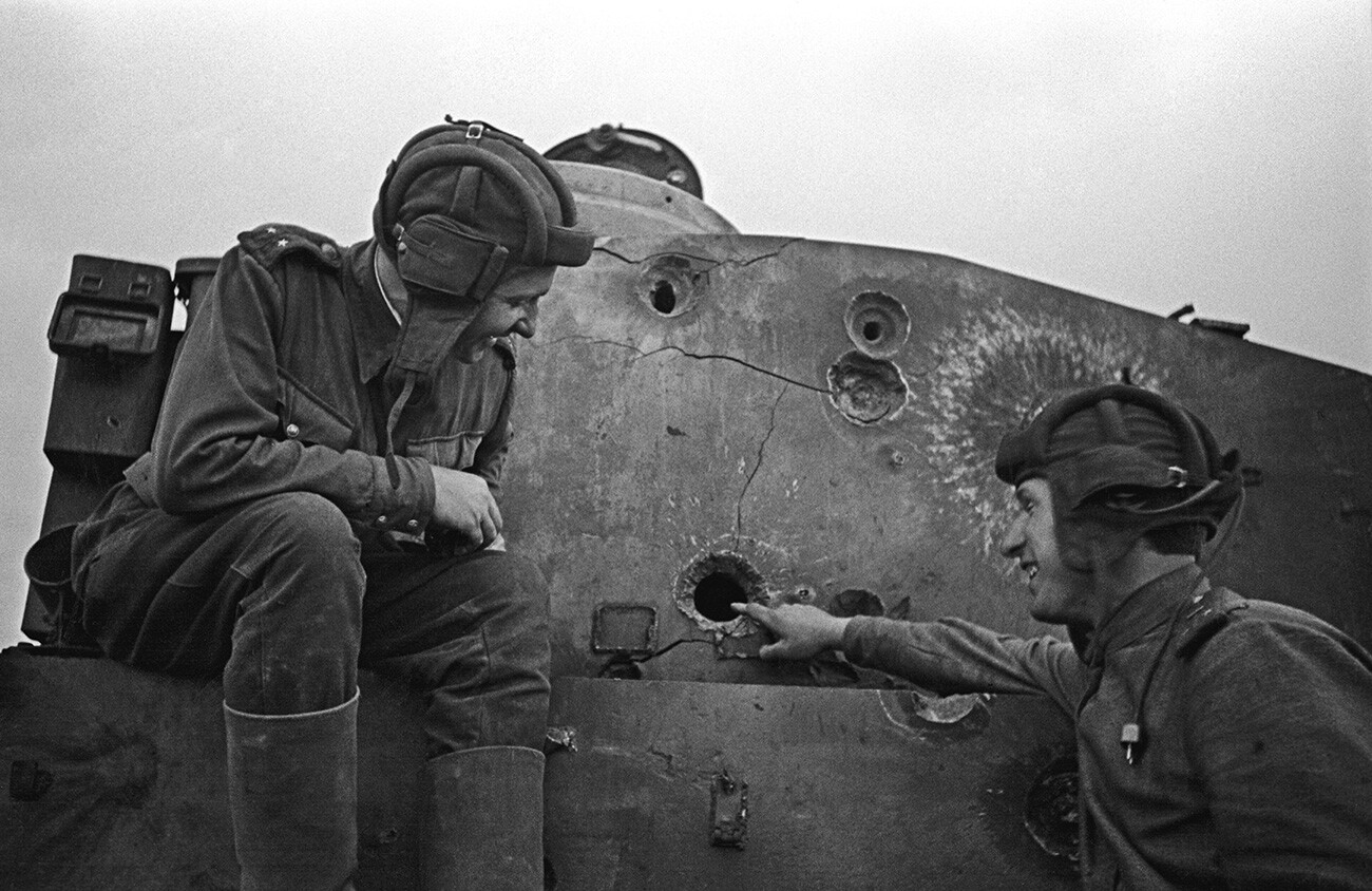 Two Soviet tankmen sitting on a disabled Tiger tank.