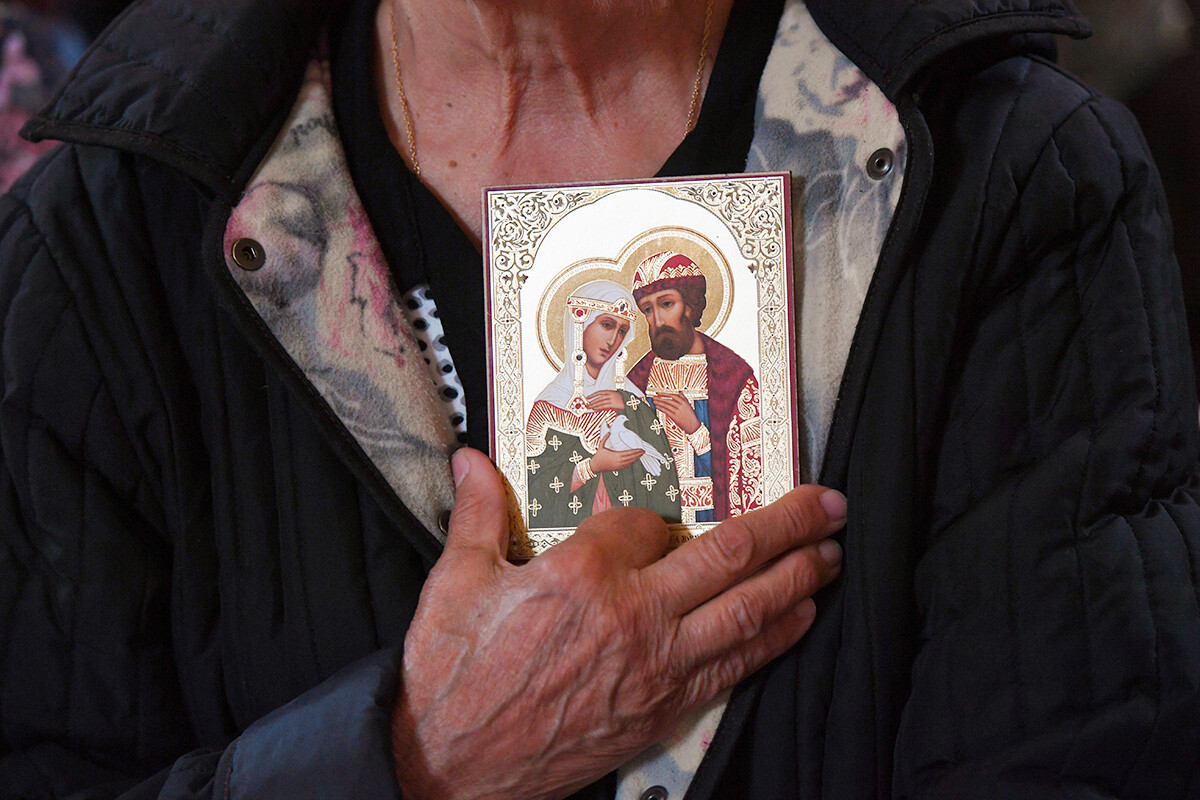 A believer holds an icon of Saints Peter and Fevronia