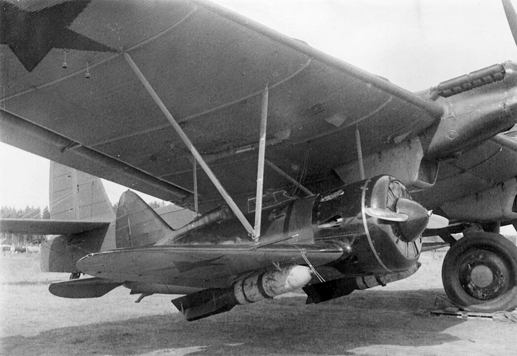 I-16 colgado bajo el ala del avión nodriza. Obsérvense las bombas en las alas del caza.