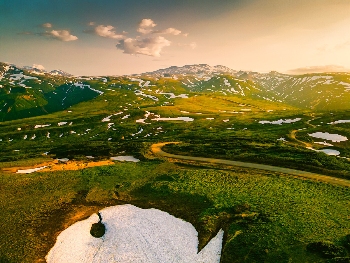 Mountains and volcanoes with snow at sunset on Vilyuchinsky pass in Kamchatka peninsula.