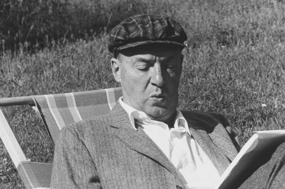 Vladímir Nabokov escribiendo sobre papel en el jardín.