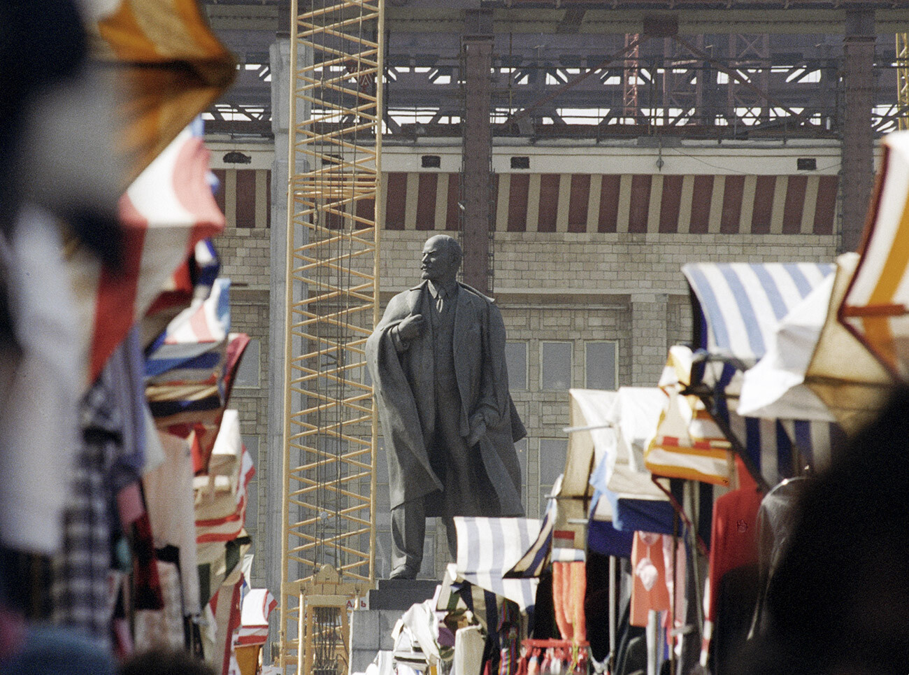 Vendedores del mercado de ropa de Luzhniki comerciando cerca del monumento a Vladimir Lenin. 