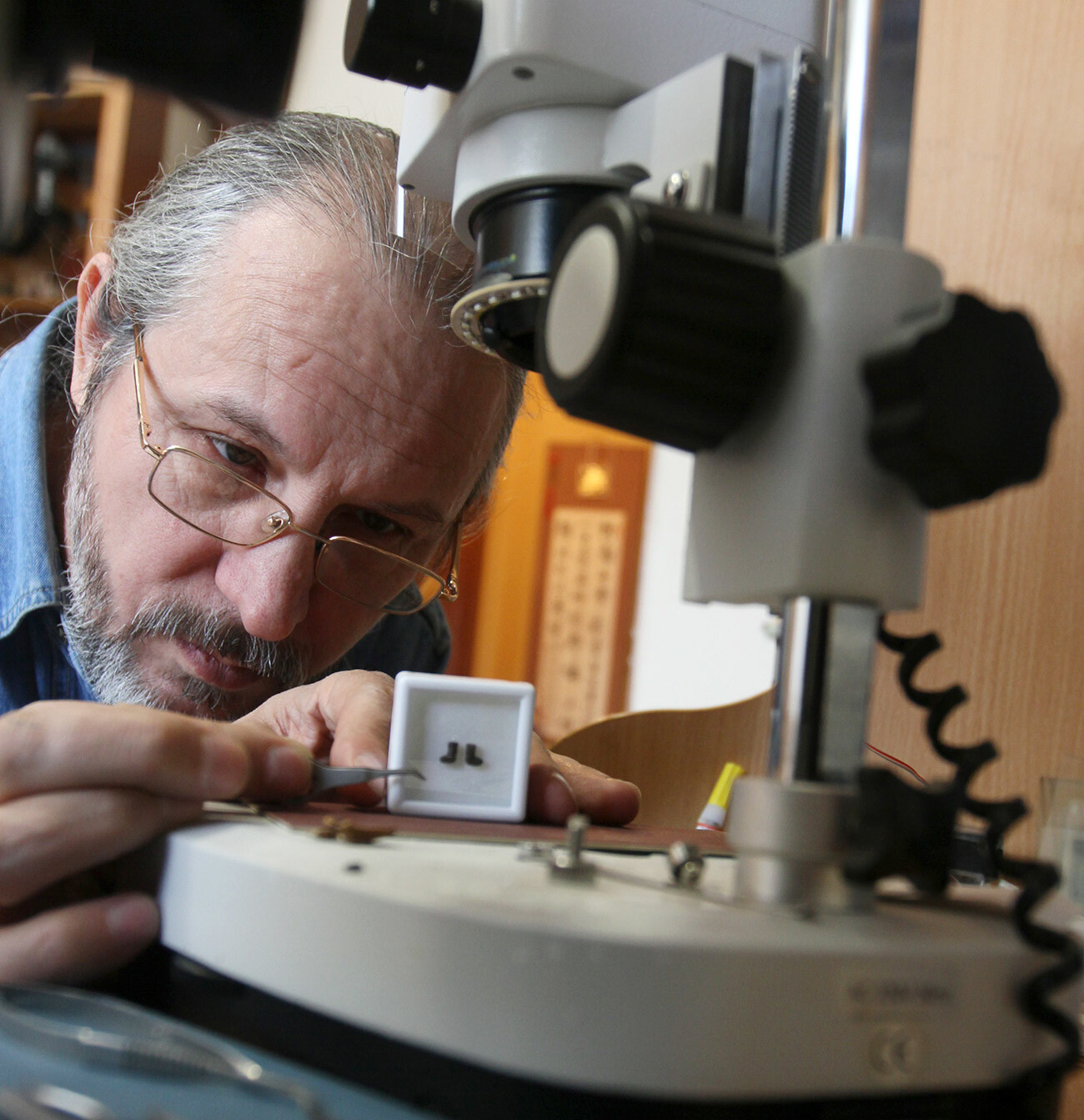 O microminiaturista de Omsk Anatóli Konenko e seu valenki (bota de feltro). Tamanho: 3 mm.