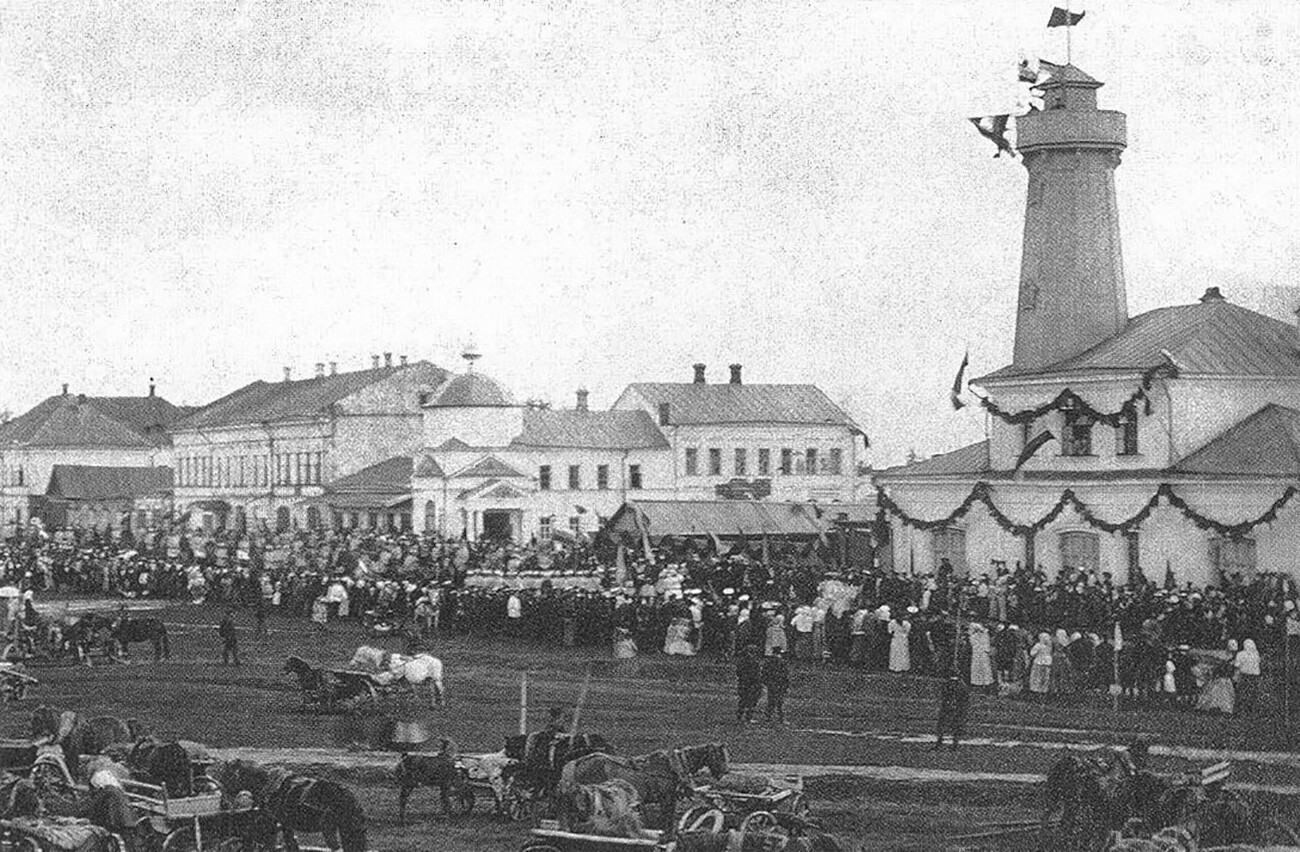 Piazza Torgovaja (o Sennaja) durante la celebrazione annuale dei vigili del fuoco di Mologa. A destra, la caserma dei pompieri con torre di avvistamento costruita su progetto dell’architetto di Jaroslavl A. M. Dostoevskij
