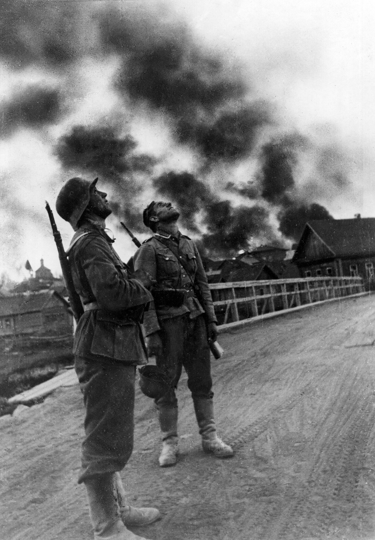 Na območju Vjazme: dva nemška pehotnika po zračnem spopadu med nasprotnimi bojnimi letali. V ozadju nekaj hiš v plamenih. Vjazma, oktober 1941