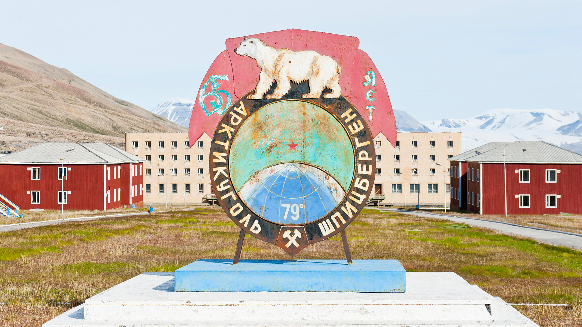 Pueblo fantasma, monumento con oso polar, escudo ruso de la empresa Arktikugol, asentamiento minero ruso abandonado Pyramiden, Spitsbergen, Svalbard, Noruega.