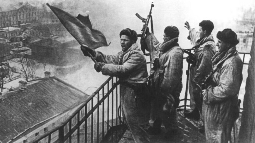 Soldati sovietici issano una bandiera rossa nella città liberata di Gatchina, vicino a Leningrado, 26 gennaio 1944