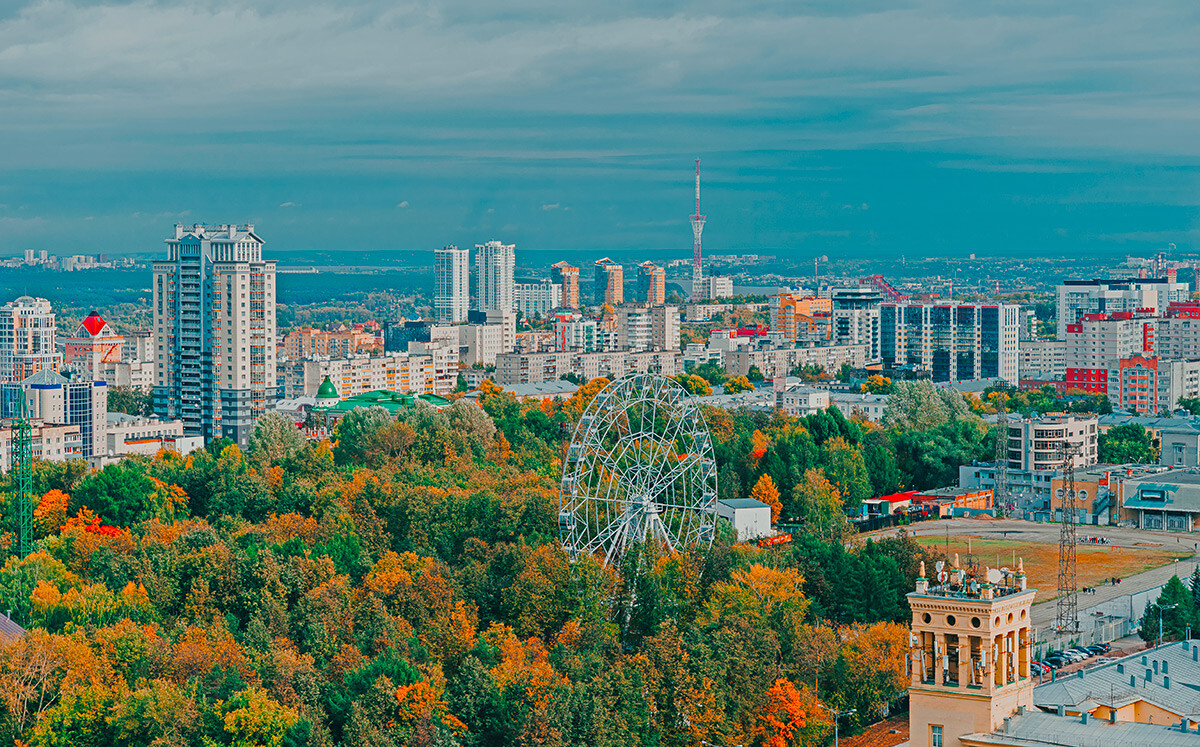 Pogled na osrednji park v Permu z višine. Panoramsko kolo med zelenimi drevesi. Panorama mesta. 