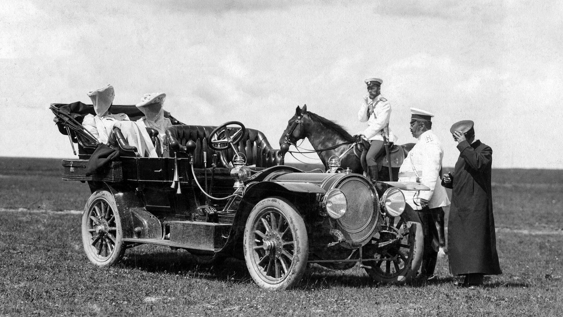 L'empereur Nicolas II à cheval devant sa première voiture, un triple phaéton Delaunay-Belleville C4 40/45 CV. À l'arrière, les princesses monténégrines Milica et Stana, à l'avant, le prince Vladimir Orlov et le chauffeur Adolphe Kégresse, à Krasnoïé Selo, été 1908