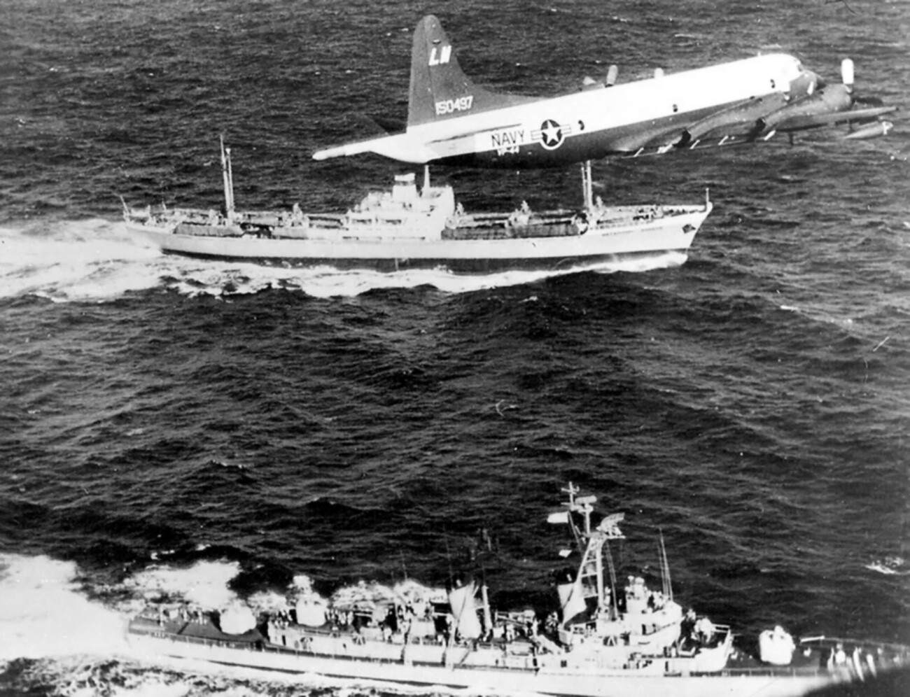 Un navire marchand soviétique fait route vers Cuba. Un destroyer de l'US Navy Barry (DD-933) suit une trajectoire parallèle et un avion Lockheed P-3A-20-LO Orion les survole. Crise des missiles de Cuba, 10 novembre 1962