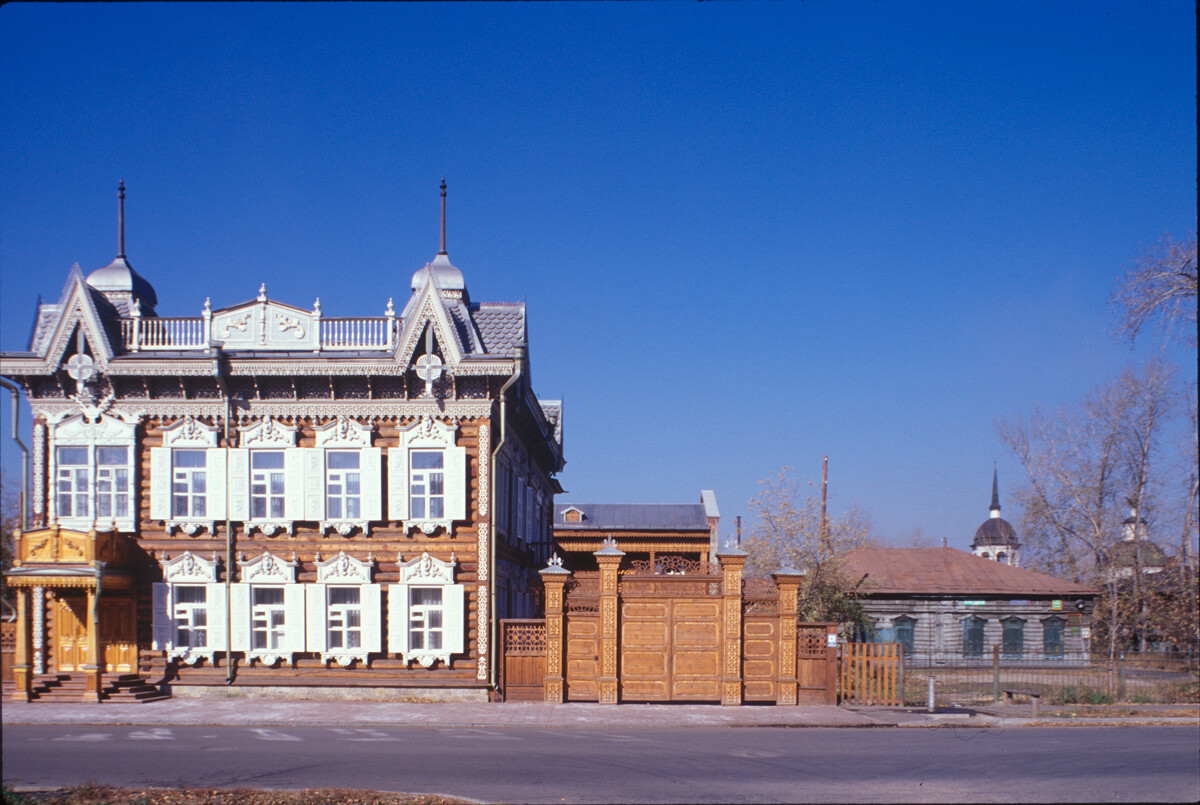 Shastin house. One of best examples of Siberian decorative wooden architecture. Core of house built around 1840 with later expansion. In 1907 bought by Apolos Shastin who added second floor & gave the house its decorative panoply. Background: Church of Transfiguration. October 3, 1999