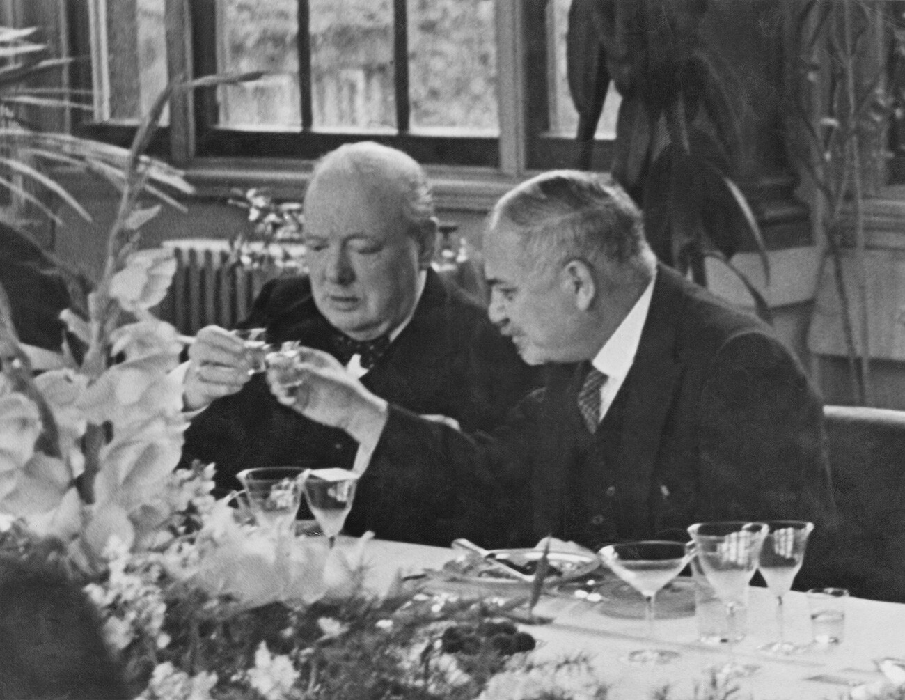 Britanski premier Winston Churchill (1874-1965, levo) pije s sovjetskim veleposlanikom Ivanom Majskim (1884-1975) na kosilu, ki ga je veleposlanik priredil za predstavnike vseh zavezniških vlad v zimskem vrtu Sovjetskega veleposlaništva v Londonu, avgusta 1941 